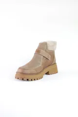 Bota corta de cuero color marrón con puntera y empeine de gamuza color beige. Tiene cuello de piel sintética color crema, cierre con velcro y suela track.