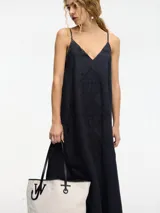 Vestido largo negro de lino con breteles finos regulables y escote en V. Presenta bordado monocromático en el frente.