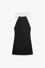 Minivestido negro con cuello halter y espalda descubierta. Presenta un panel blanco en la parte superior delantera y forro interior.