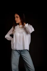 Camisa color crema con cuello alto y mangas largas con volados en los puños. Presenta detalles de crochet y broderie en el frente.