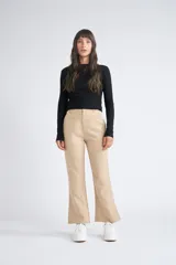 Pantalón de dama beige con pasa cinto y pierna trompeta, de corte ajustado.