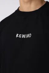 Remera color crema de corte oversize con la palabra "Rewind" bordada en el frente.