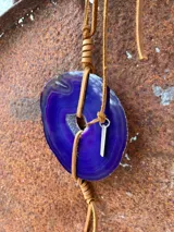 Collar con dije de ágata azul y blanca, con cordón de cuero marrón ajustable.