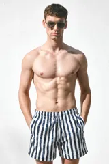 Short de baño blanco con rayas verticales azules, cintura elástica con cordón ajustable, bolsillos laterales y bolsillo trasero con cierre autoadherente. Cuenta con suspensor interior de malla suave.