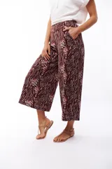 Pantalón capri negro con estampado abstracto en tonos beige, gris y marrón.