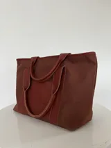 Bolso tote negro de lona con apliques de cuero y doble asa de mano.