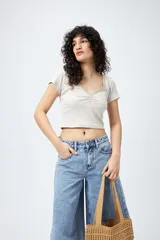 Remera corta negra de punto acanalado con escote en V fruncido y puntilla en el borde.