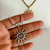 Collar plateado con dije en forma de sol con espiral en el centro.