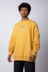 Buzo color mostaza de corte oversize con cuello redondo y tela rústica. Presenta un pequeño estampado en el pecho con un pato y olas.