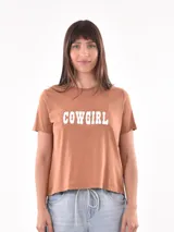 Remera color marrón con estampado frontal de la palabra 'COWGIRL' en letras blancas mayúsculas.