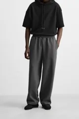 Pantalón jogger wide fit color gris oscuro, confeccionado en tejido de algodón compacto con elasticidad. Cuenta con cintura elástica ajustable con cordón, pliegues frontales, bolsillos delanteros y bolsillo trasero de parche.