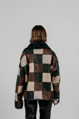 Buzo de cuero lanar con diseño de patchwork en bloques de color, combinando tonos camel, marrón oscuro y beige.