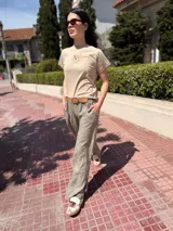 Pantalón marrón de lino con bordados blancos en los laterales y bolsillos. Corte recto y cintura con elástico.