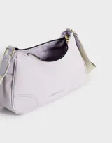 Bandolera color beige con correa blanca regulable y desmontable, tag frontal en relieve y cierre superior.