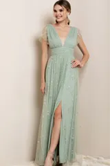 Vestido largo de fiesta color verde agua, con escote en V, mangas cortas de tul y falda con tajo lateral. Presenta apliques de estrellas plateadas en toda la prenda.