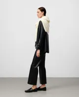 Pantalón flare de tiro alto, color azul marino oscuro, con acabado de efecto cuero. Presenta un corte ancho que se ensancha desde la rodilla hasta el tobillo.