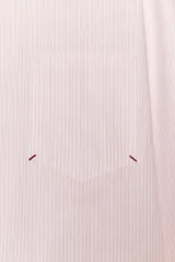 Camisa de cuello solapa y manga larga con puño doble abotonado. Cierre frontal con botones y estampado a rayas verticales rosas y blancas.