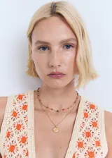 Top de crochet color crudo con flores naranjas, sin mangas, con escote en V y cierre frontal con lazos.