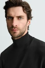 Jersey negro de punto fino con cuello alto y manga larga.