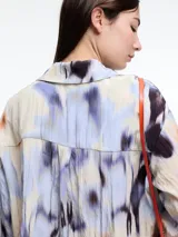 Camisa de manga larga confeccionada en viscosa crinkled con estampa de manchas. De silueta amplia y fluida, con bolsillos frontales grandes, tajos laterales y largo extendido en la espalda.