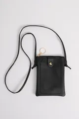 Funda porta celular negra con correa larga para colgar al hombro, bolsillo frontal y cierre con broche a presión. Incluye llavero dorado.