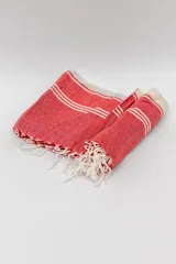 Lona de playa rectangular con diseño estampado a rayas rojas y blancas.