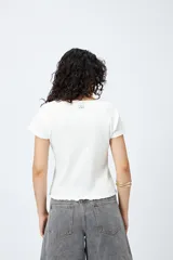 Remera color beige de punto acanalado con silueta relajada y manga corta raglán. El ruedo tiene terminación ondulada. El tejido con elasticidad ligera brinda comodidad y movimiento.