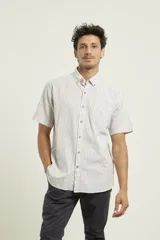 Camisa de manga corta a rayas verticales azules y blancas, con cuello abotonado y bolsillo en el pecho.