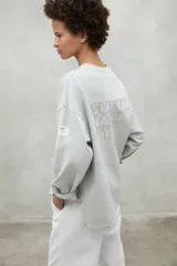 Buzo color gris claro de algodón orgánico y reciclado, con cuello redondo y mangas largas.