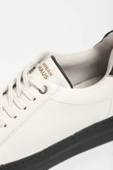 Zapatillas urbanas blancas con detalle azul en el talón y suela de goma.