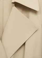 Trench beige de algodón con cuello con solapa, trabillas, manga larga con trabillas, cierre delantero, solapas con muesca, dos bolsillos laterales, diseño recto, cinturón desmontable y forro interior.