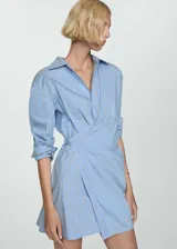 Vestido camisero corto celeste con rayas verticales blancas y marrones, con cierre cruzado y mangas largas con puños abotonados.