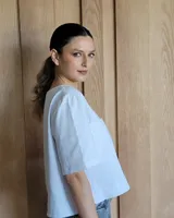 Remera negra con cuello redondo y mangas cortas, con detalle de pespuntes blancos en cuello, mangas, bolsillos frontales y ruedo.