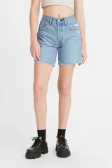 Short de jean azul claro, tiro medio, con largo hasta la mitad del muslo y corte relajado. Presenta desgaste y roturas sutiles en la zona del bolsillo delantero.