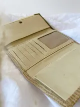 Billetera de cuero turquesa, blanco y beige con diseño texturizado. Tiene sistema de cierre con broche y monedero externo.