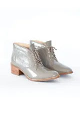 Botín gris de cuero charol brillante, con cordones frontales y tacón bloque de madera clara de 6 cm.