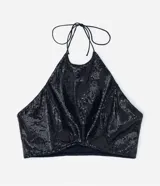 Blusa cropped de lentejuelas negras con cuello halter y espalda descubierta.