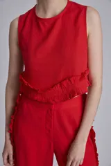 Conjunto de dos piezas color marrón, compuesto por un top sin mangas con volado en el ruedo y un pantalón ancho de tiro alto con volados decorativos a lo largo de las costuras laterales.