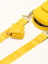 Bolso pequeño color amarillo con correa ajustable y compartimento adicional.