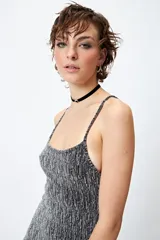 Vestido corto de lurex plateado y negro, sin mangas, con breteles finos regulables y volados tipo balloon desde la cadera.
