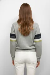 Buzo gris con mangas raglán y bandas horizontales en azul, blanco y verde en los brazos.