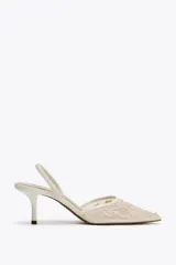 Zapato destalonado color blanco hueso, con tacón fino y punta fina. Capellada de mesh con bordados florales.
