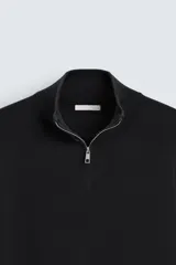 Jersey negro de punto con cuello perkins y cierre frontal de cremallera.