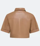 Camisa de manga corta confeccionada en material sintético color beige. Tiene cuello camisero, cierre de botones en forma de corazón, dos bolsillos con solapa y corte cropped.