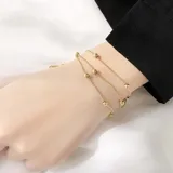 Pulsera dorada de acero quirúrgico con triple cadena y cuentas.