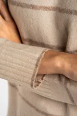 Sweater color crema con rayas horizontales en tonos marrón, bordeaux y beige.