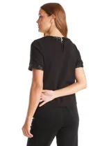 Blusa negra de modal con cuello a la base y espalda con abertura de ojal y botones. Presenta apliques de lentejuelas en el cuello y las mangas.