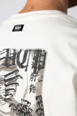 Remera color crudo de corte oversize con estampado pequeño en el centro del pecho.
