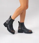 Botas Chelsea de cuero vacuno negro con elásticos laterales, cierre interno y suela de goma artesanal.