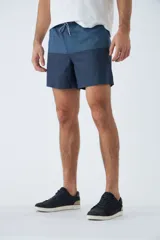 Short de baño celeste con estampado de líneas curvas en azul. Cuenta con cintura elástica con cordón ajustable, dos bolsillos laterales, un bolsillo trasero, suspensor interno y logo bordado.